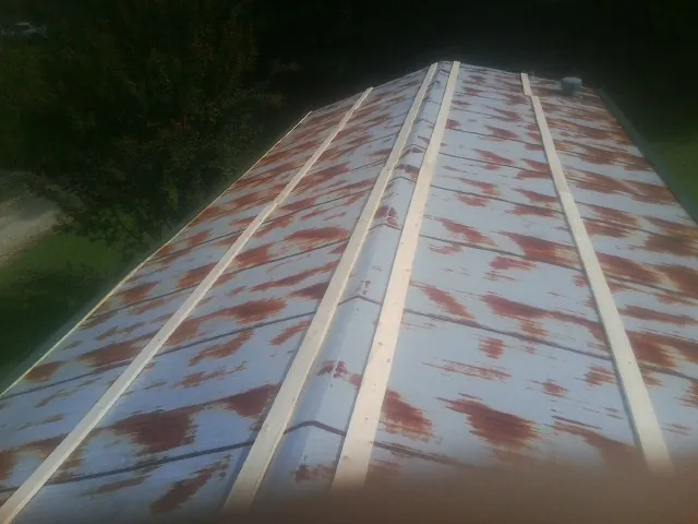 Rusted metal roof panels with new wood purlins before replacement — Storm Damage Roof Repair in North Grosvenordale by Roofing Brothers