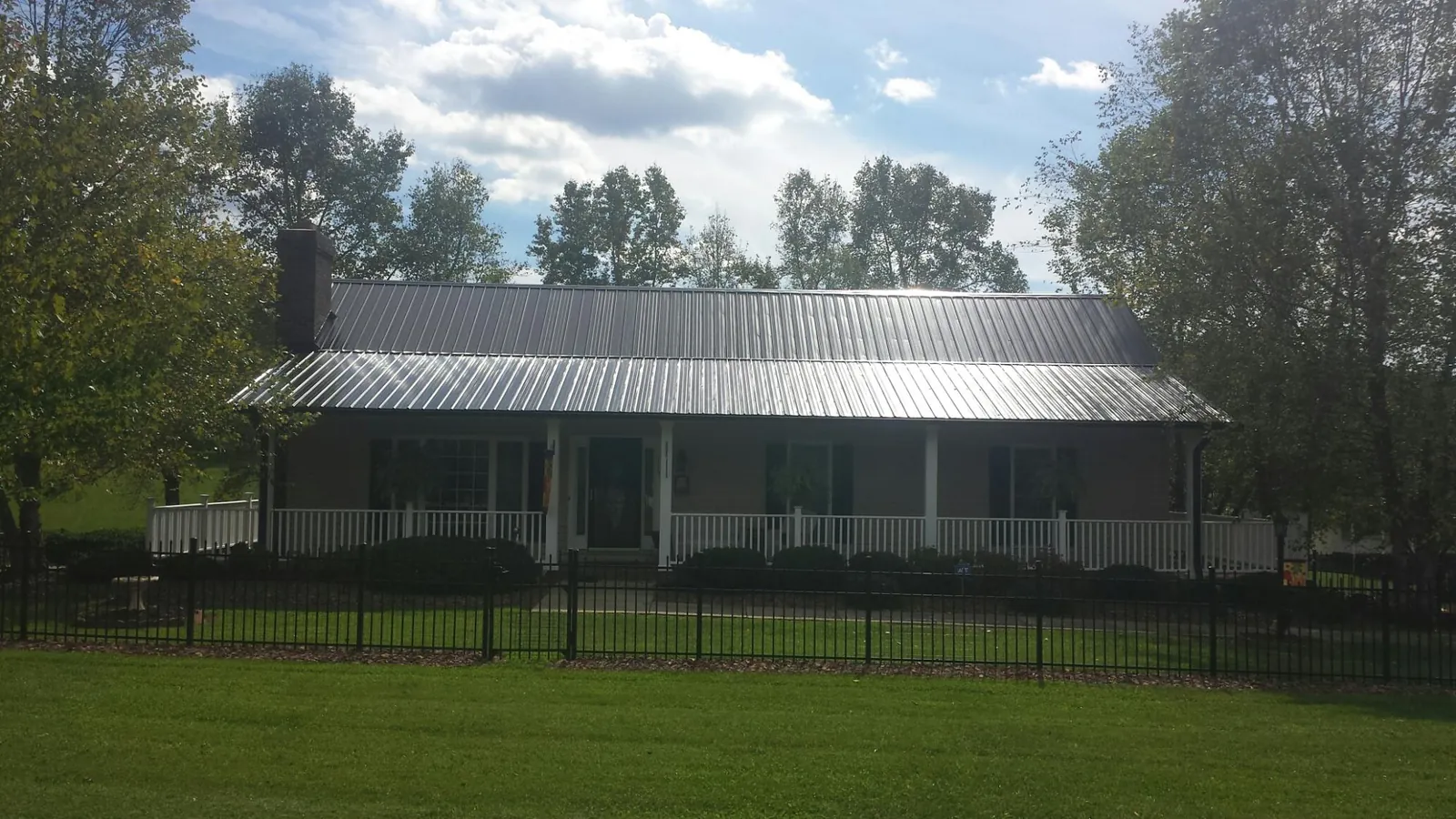 Gray metal roof on a brick ranch with a full width front porch — Gutter Guard Installation work by our crew in North Grosvenordale