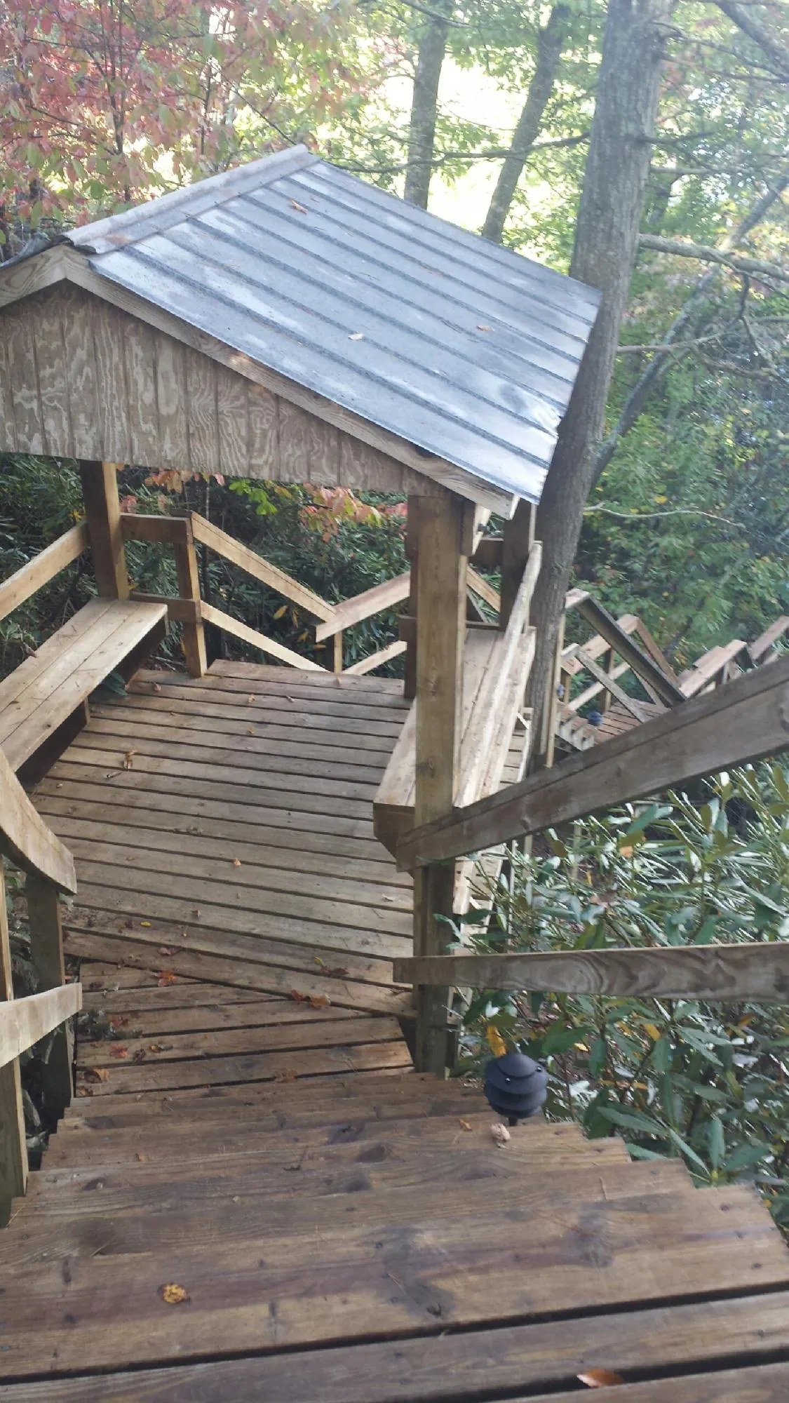 Metal roofed shelter over wooden steps on a wooded walkway — Skylight Repair & Installation work by our crew in North Grosvenordale