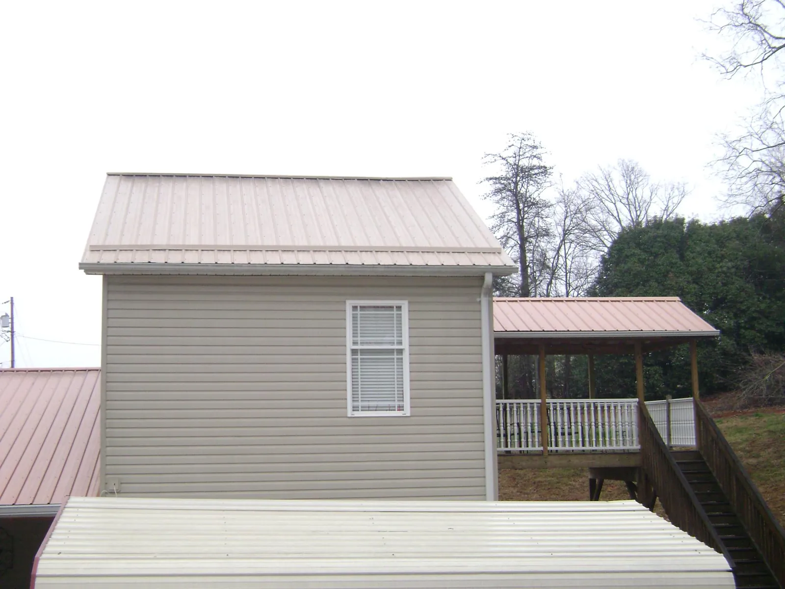 Tan metal roofs on a two story addition and attached porch, from a Roof Replacement job in North Grosvenordale