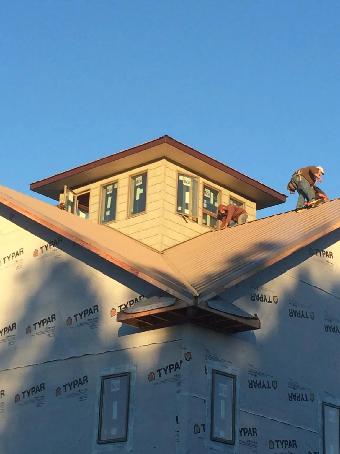 Roofers working around a rooftop cupola on a new metal roof at sunset — Roof Waterproofing in North Grosvenordale by Roofing Brothers